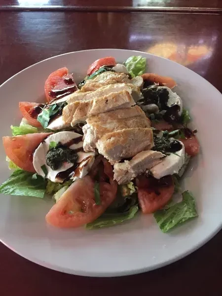 Overhead grilled chicken, lettuce, tomato, mozzarella salad with balsamic and pesto.