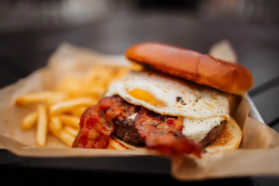 Beef burger with bacon, fried egg, and golden fries.