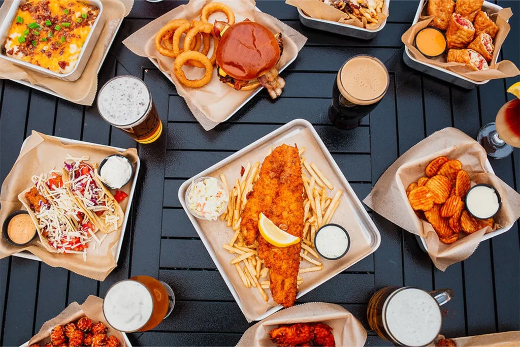 Overhead shot of a table full of diverse casual food and drinks.