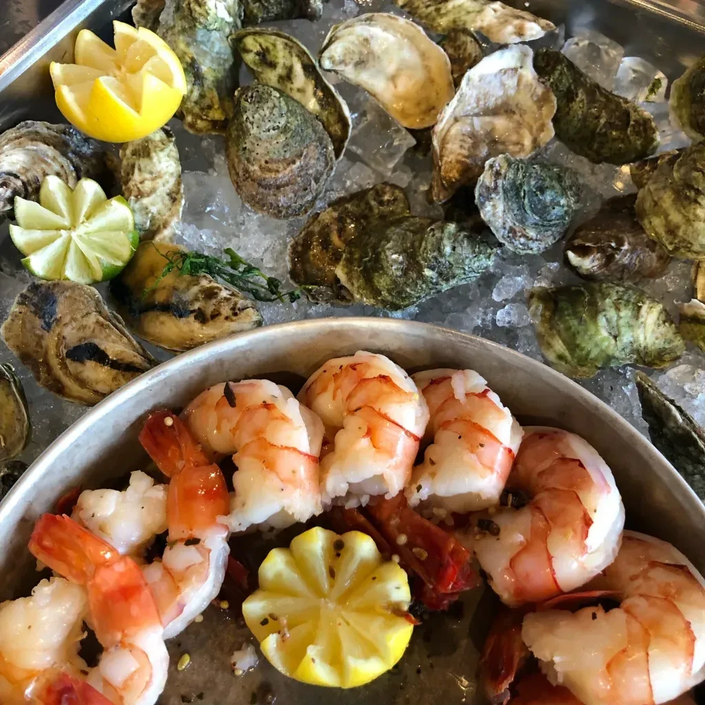 Raw oysters and cooked shrimp on crushed ice with lemon and lime.