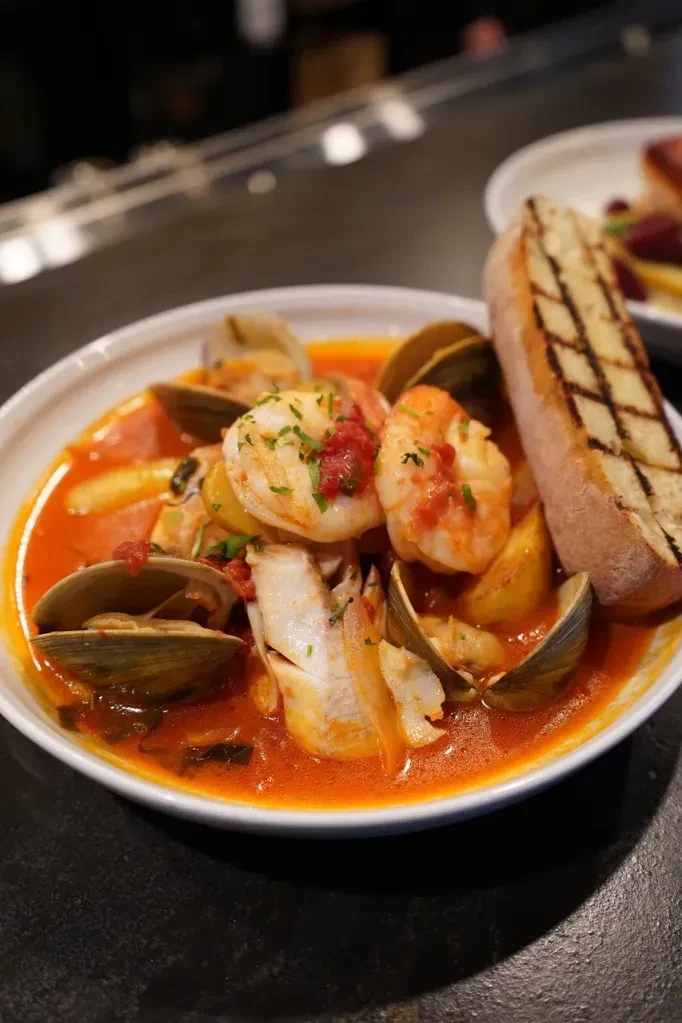 Steaming seafood stew with shrimp, clams, fish, and grilled bread.