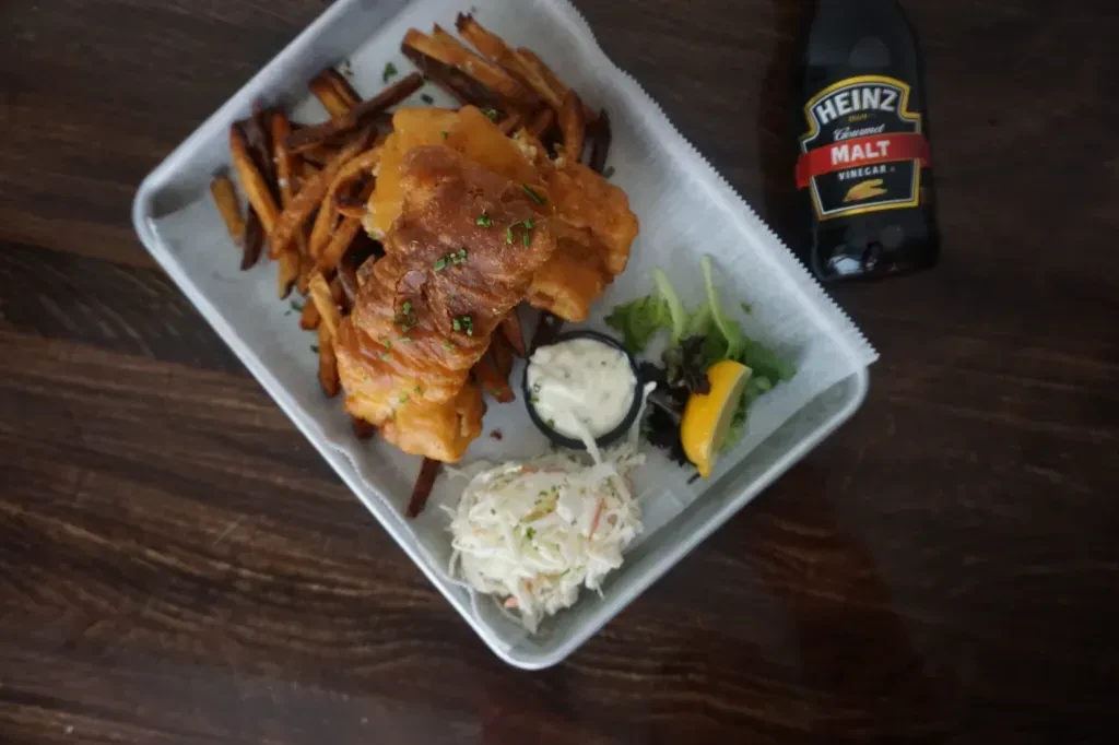 Top-down: Fish and chips with tartar, coleslaw, lemon, and malt vinegar.