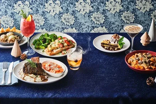 A table laden with various dishes, cocktails, desserts, and festive decorations.
