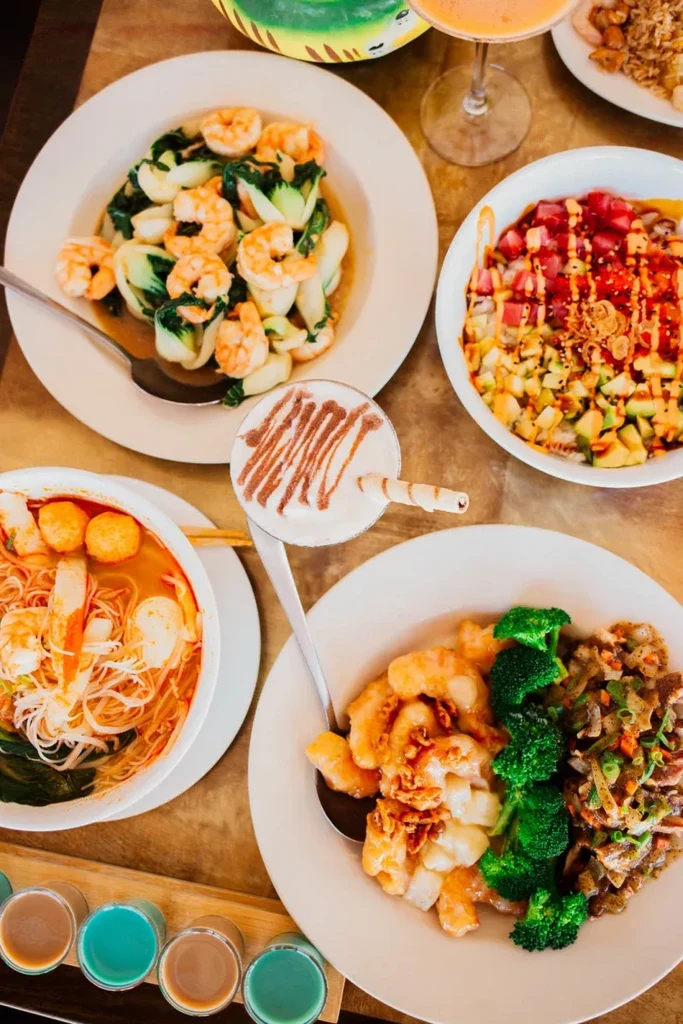 Variety of colorful Asian dishes and beverages on a wooden table.