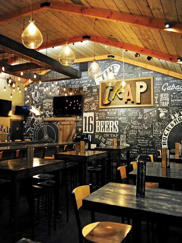 Modern rustic bar interior featuring chalkboard walls and warm lighting.