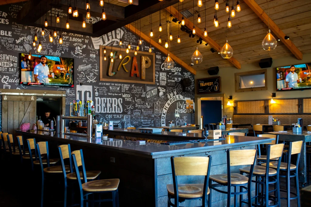 Rustic bar with chalkboard art, Edison bulbs, and sports on TVs.