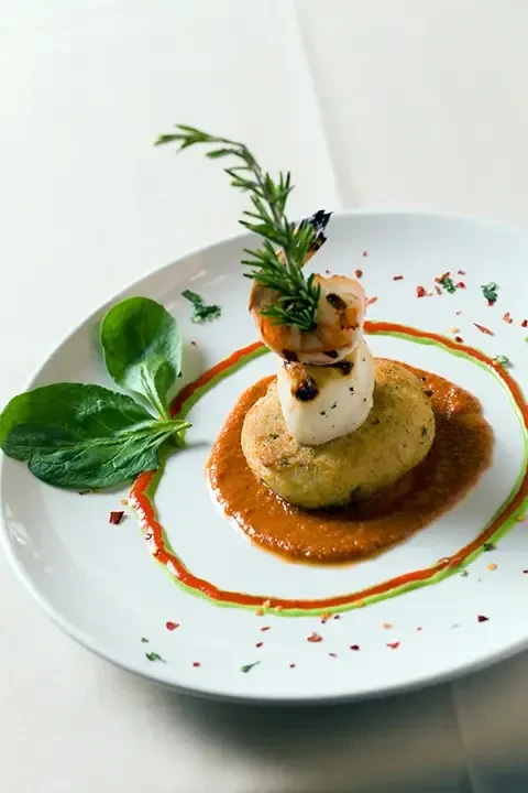 Meticulously plated seafood: fried base, scallop, shrimp, sauces, and rosemary.