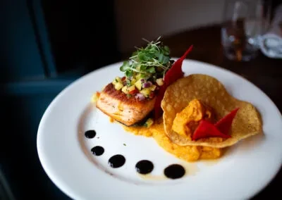 Plated pan-seared fish with fruit salsa and puree in a restaurant.