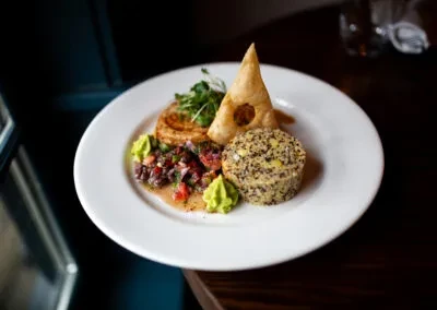 Plated dish with golden pastry, grain mold, savory tart, green puree, salsa.