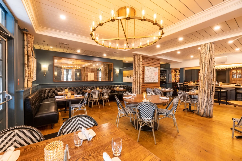 Elegant restaurant interior blending rustic and modern elements, with bar visible.