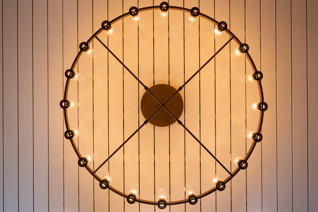 Circular dark metal light fixture with 24 warm bulbs, viewed from below.