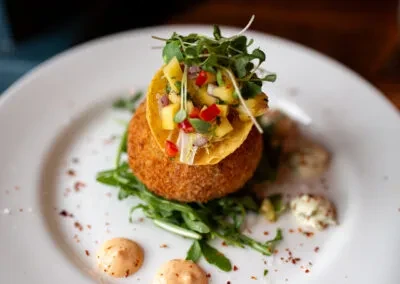 Golden fried croquette with mango salsa, arugula, and orange sauce.