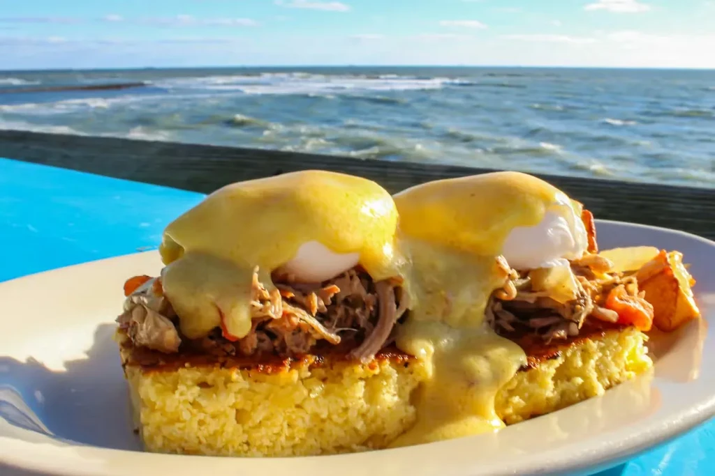 Eggs Benedict with pulled pork, cornbread, potatoes, ocean view.