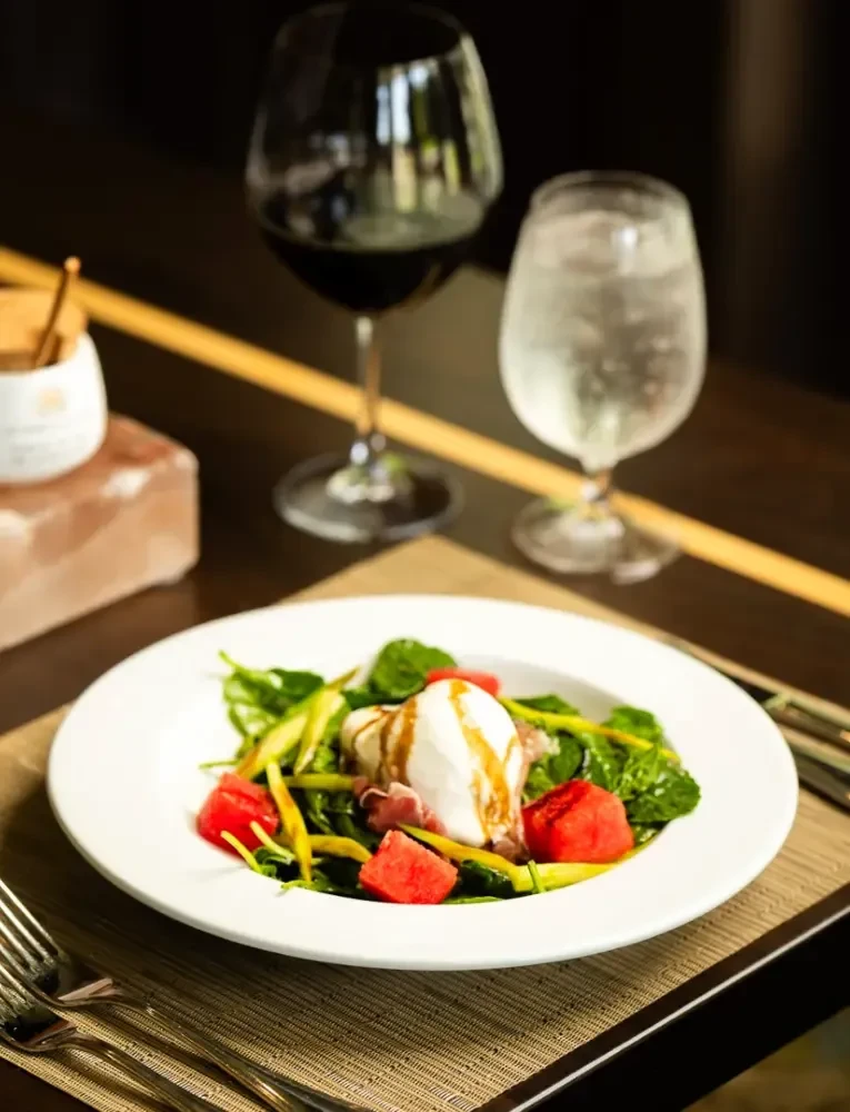 Burrata, prosciutto, watermelon, and greens drizzled with balsamic glaze.