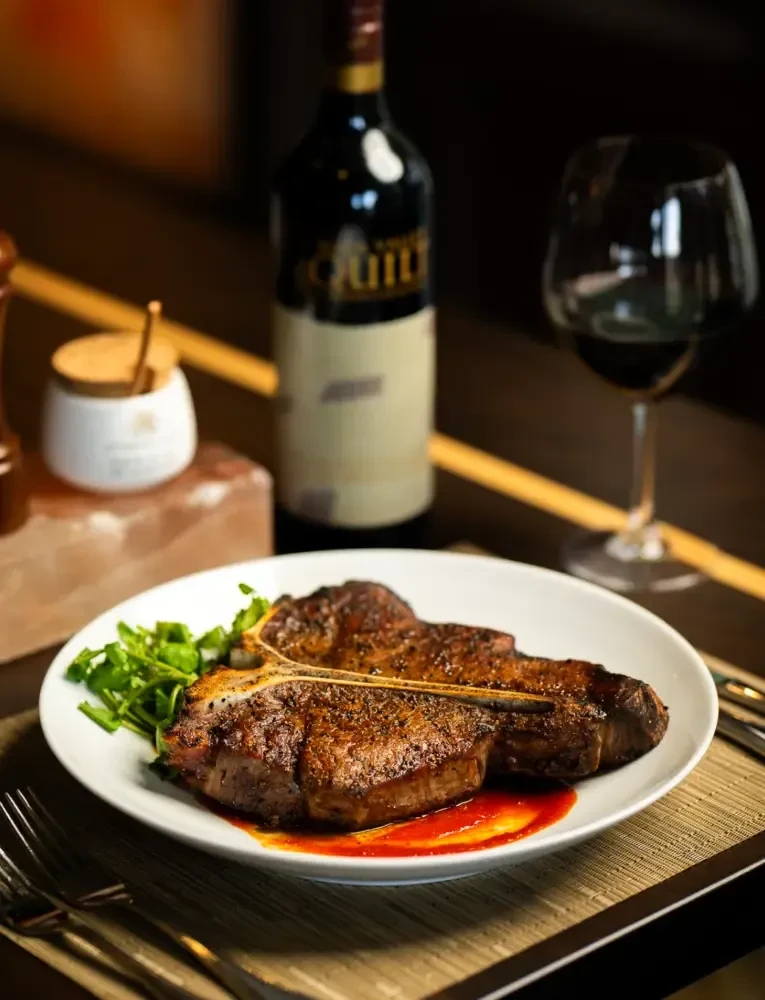 Seared T-bone steak, green garnish, wine, and Himalayan salt block.