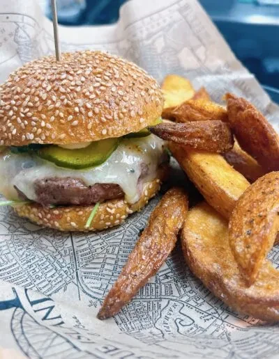 A cheeseburger and potato wedges served on vintage map paper.