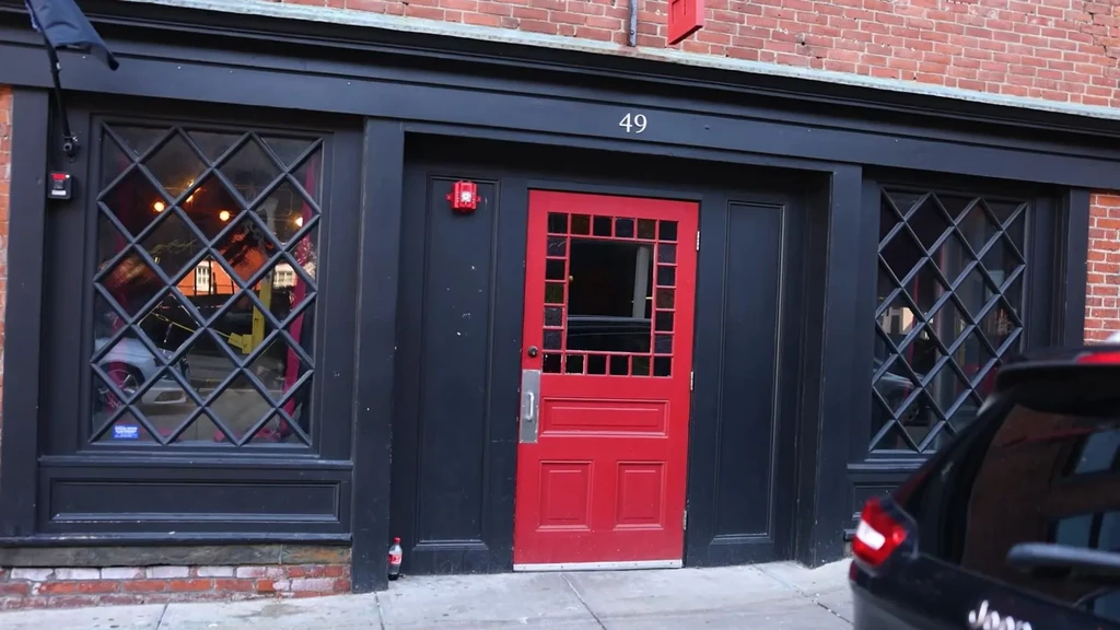 Building facade with red door, number 49, and diamond-grid windows.