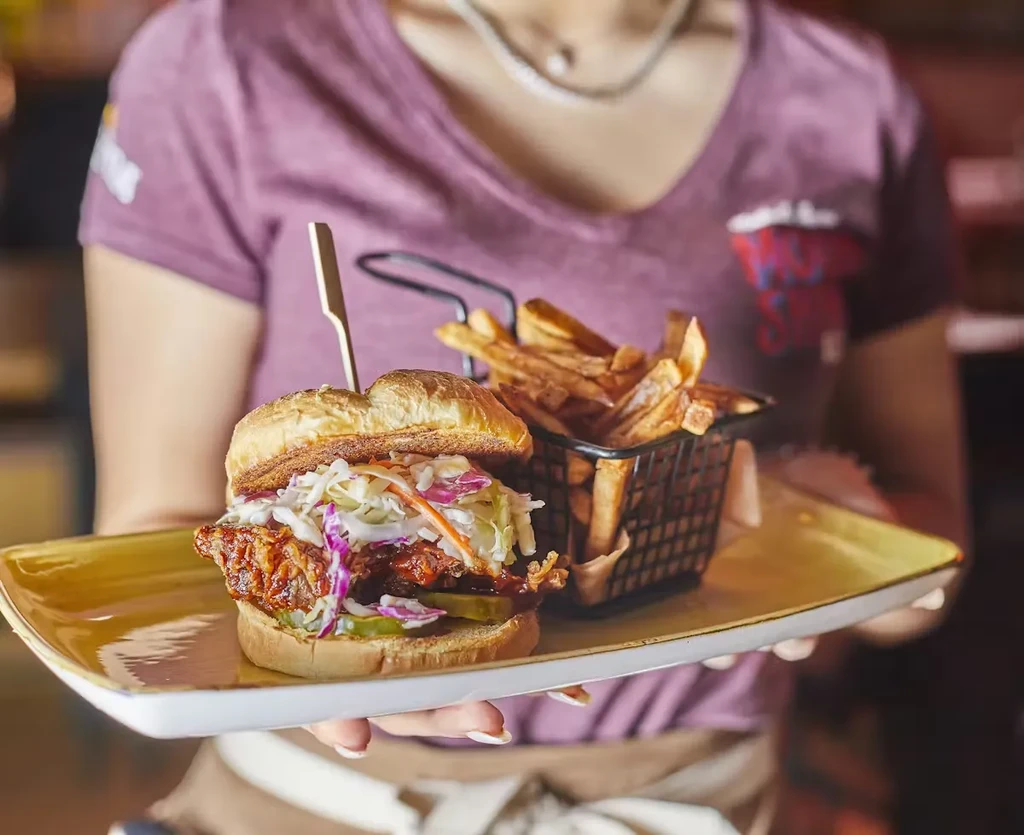 Fried chicken sandwich, coleslaw, and fries held on a mustard-yellow plate.