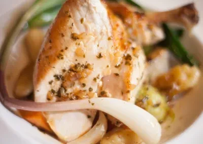 Roasted chicken breast, seasoned with herbs, served with onions and vegetables.