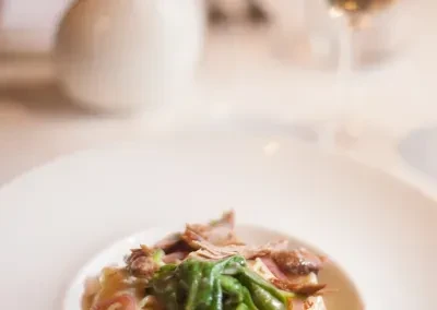Finely sliced meat, green vegetables, and sauce on white plate.