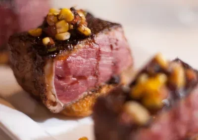 Seared medium-rare meat slice topped with corn relish on toast.