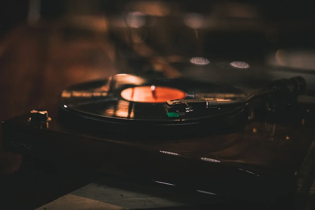 Close-up of a turntable playing a vinyl record with a green cartridge.