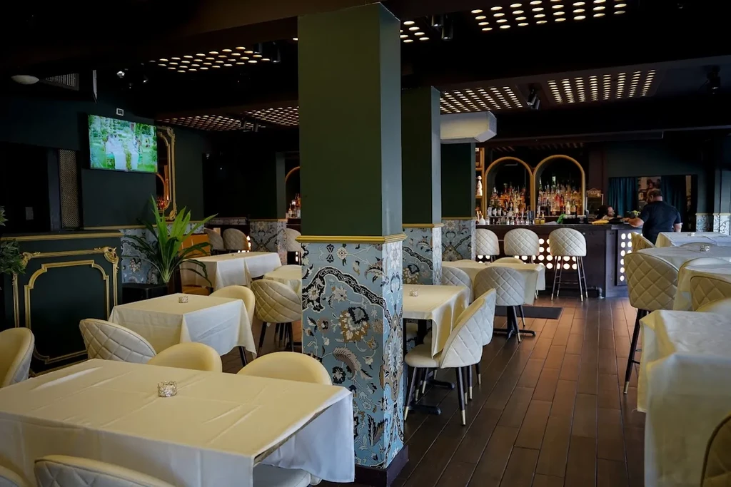 Upscale restaurant interior with patterned pillars, dining tables, and bar.