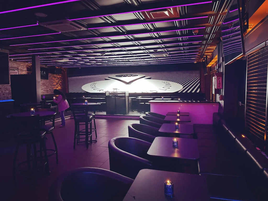 Modern restaurant lounge interior with dominant purple neon lighting.