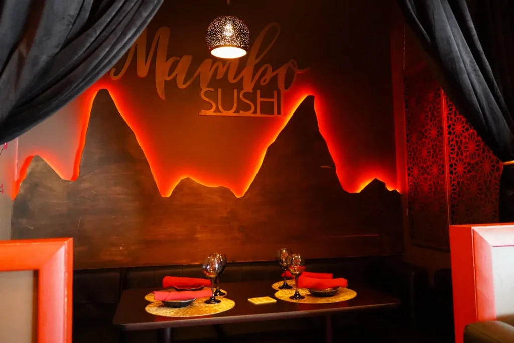 Mambo Sushi restaurant booth with red lights and table for two.