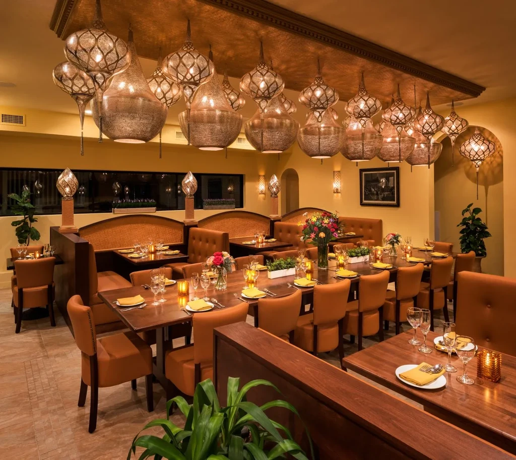 Elegant restaurant dining room featuring ornate lamps, warm lighting, and set tables.