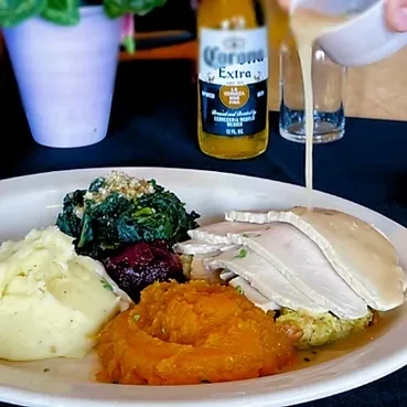 Holiday meal: turkey, mashed potatoes, cranberry sauce, and gravy pouring.