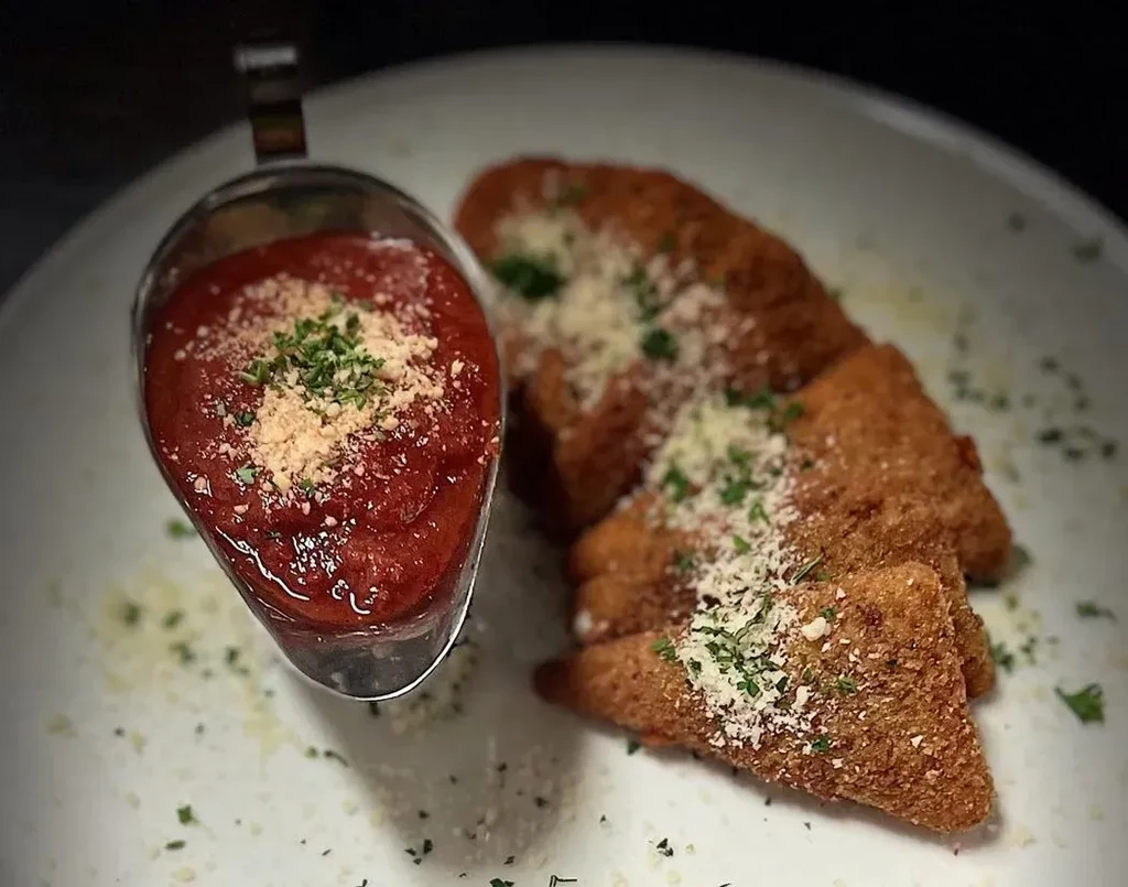 Triangular fried appetizers with cheese, herbs, and marinara sauce.