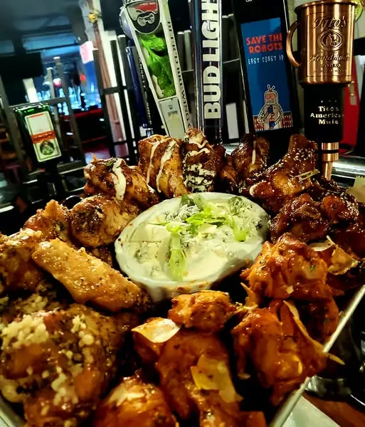 Platter of chicken wings with various sauces and dip in a bar.