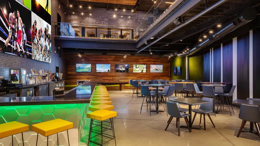 Modern two-story sports bar with green LED bar and sports screens.