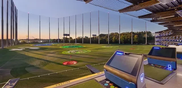 Wide Topgolf driving range with targets, empty bays, and netting.