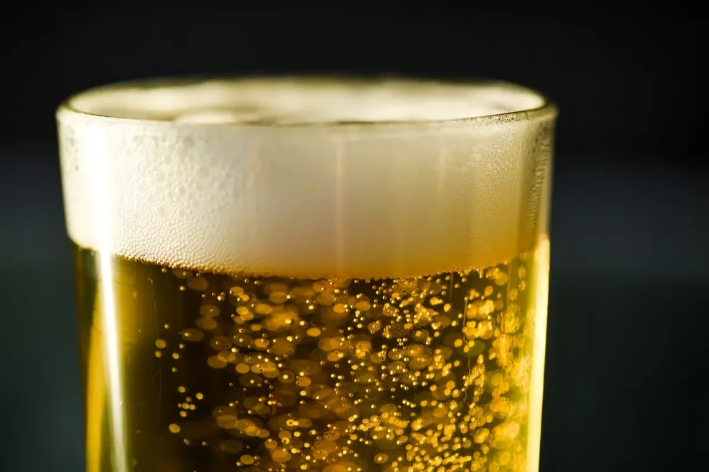 Effervescent golden beer with creamy white foam in a glass.