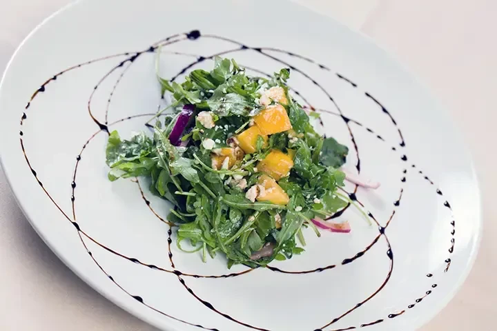 Arugula salad with mango, feta, red onion, and balsamic glaze.