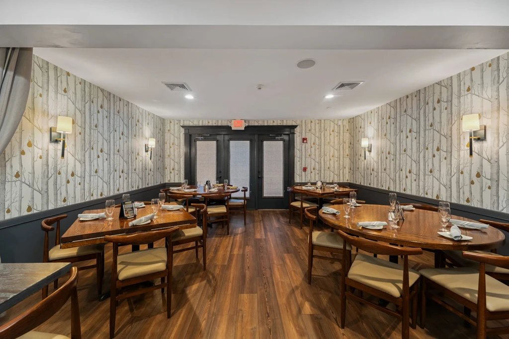 Empty dining room with set tables, birch wallpaper, and wooden floors.