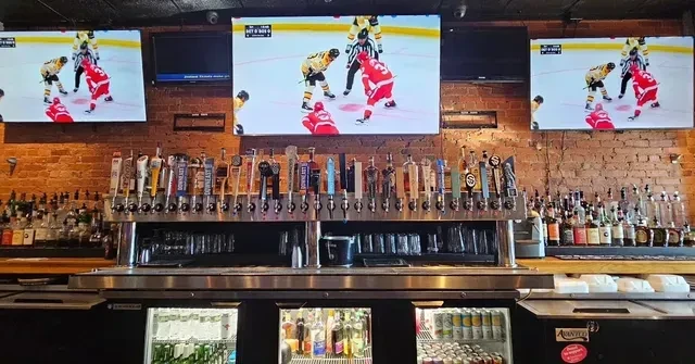 Sports bar with diverse beer taps and hockey game on three TVs.