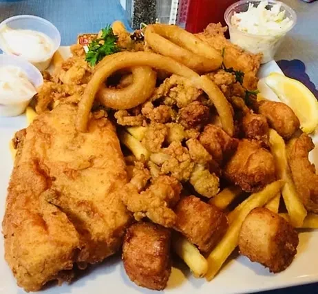 Fried fish and seafood platter with french fries and sauces.