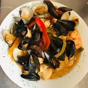 Mixed seafood dish with mussels, clams, shrimp, peppers, and reddish sauce.