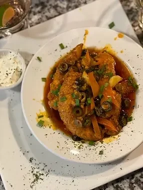 Sauced fried chicken with olives, carrots, green onions, and creamy side dip.