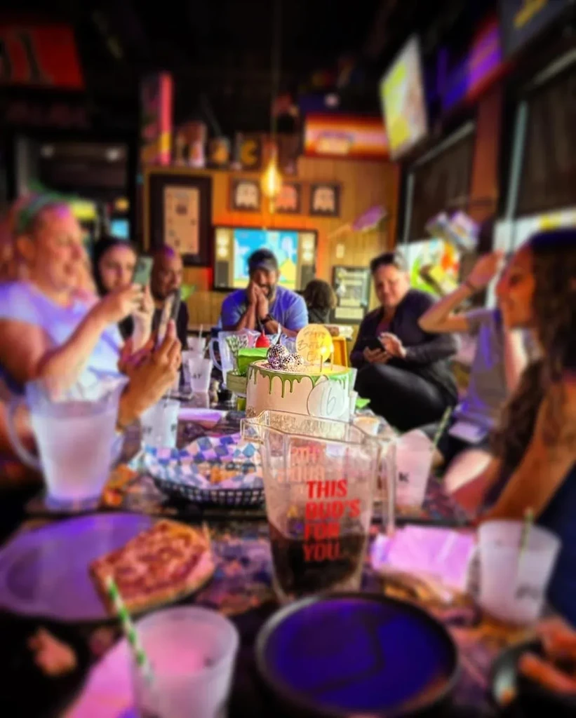 16th birthday cake, drinks, and blurred people in a restaurant.