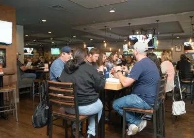 Bustling casual restaurant with patrons eating, drinking, and watching TVs.