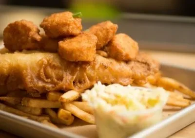 Fried fish, french fries, fried seafood, and coleslaw on a metal tray.