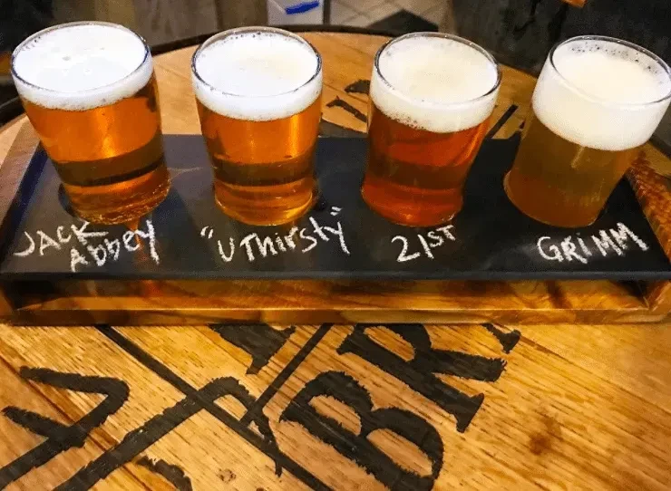 Four light to amber beers in a flight with chalk labels.