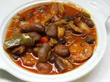 Close-up: Hearty reddish-brown stew with beans, chorizo, and peppers.