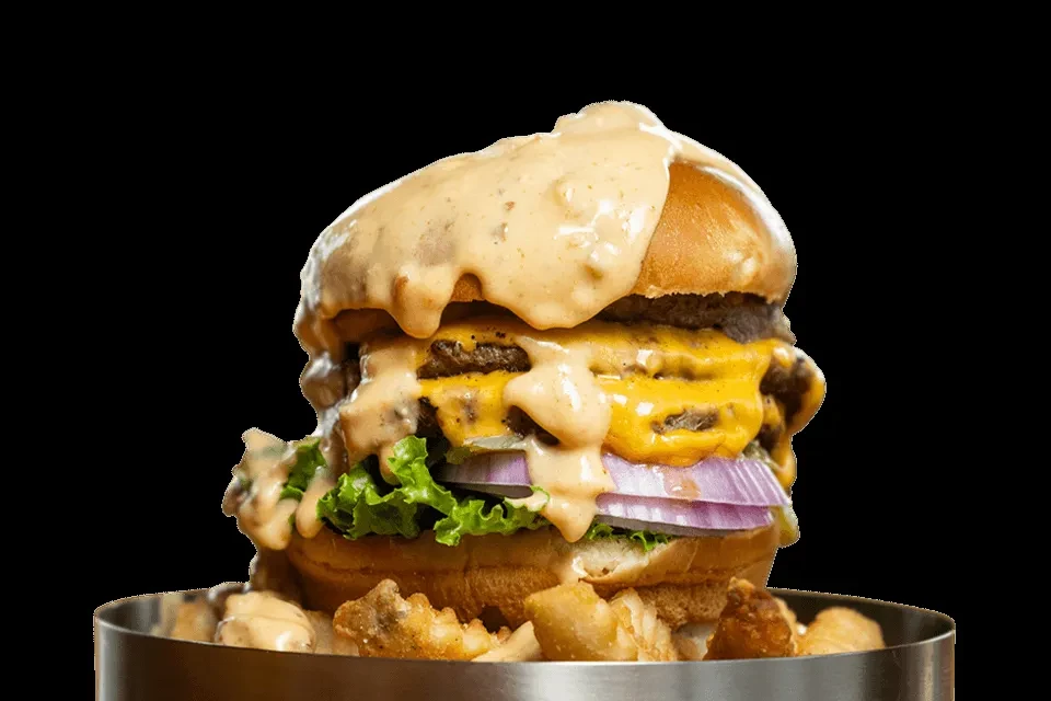 Large double-patty burger with sauce, cheese, lettuce, onion, and fries.