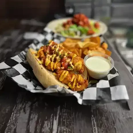 Close-up: Fried sandwich with salsa, creamy sauce, and potato chips.