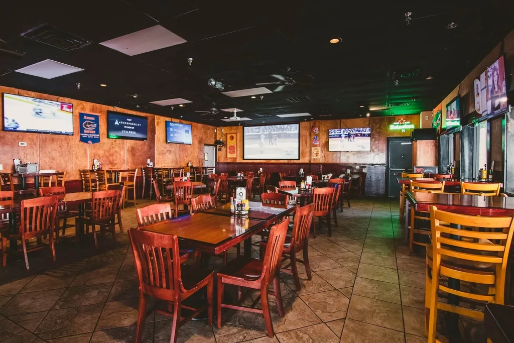 Empty sports bar interior with many screens showing games.
